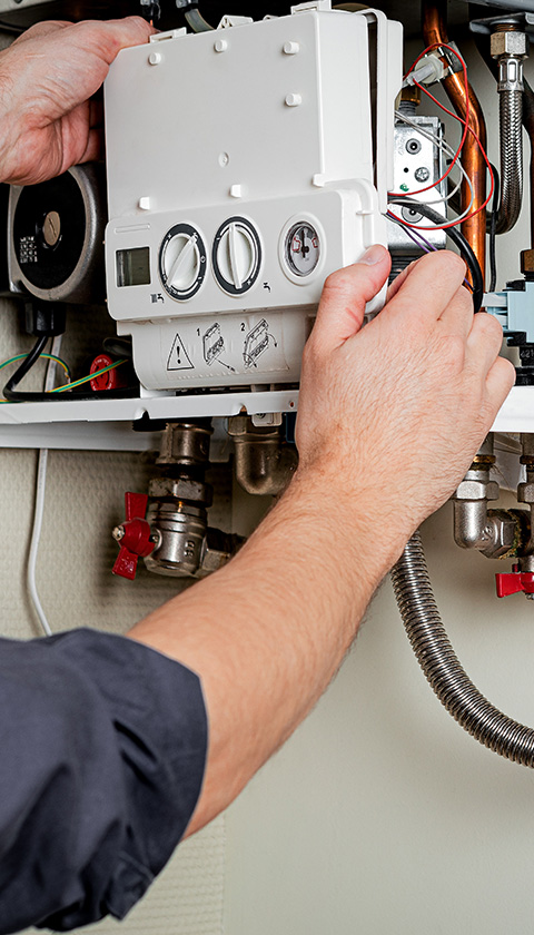 hands adjusting a heating control panel showing temperature settings and warning symbols related to plumbing systems and installation tips for seven heating systems